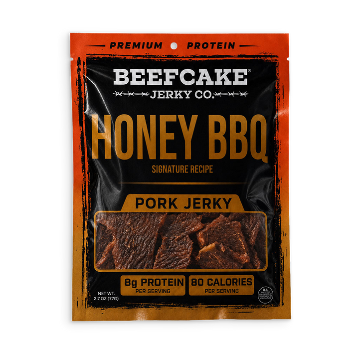 A package of Beefcake Jerky Co. Honey BBQ Pork Jerky, featuring a black and orange design with a clear window showing the jerky pieces inside.