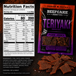 A package of Beefcake Jerky Co. Teriyaki Pork Jerky is shown alongside a Nutrition Facts label and several pieces of the jerky on a dark textured background.