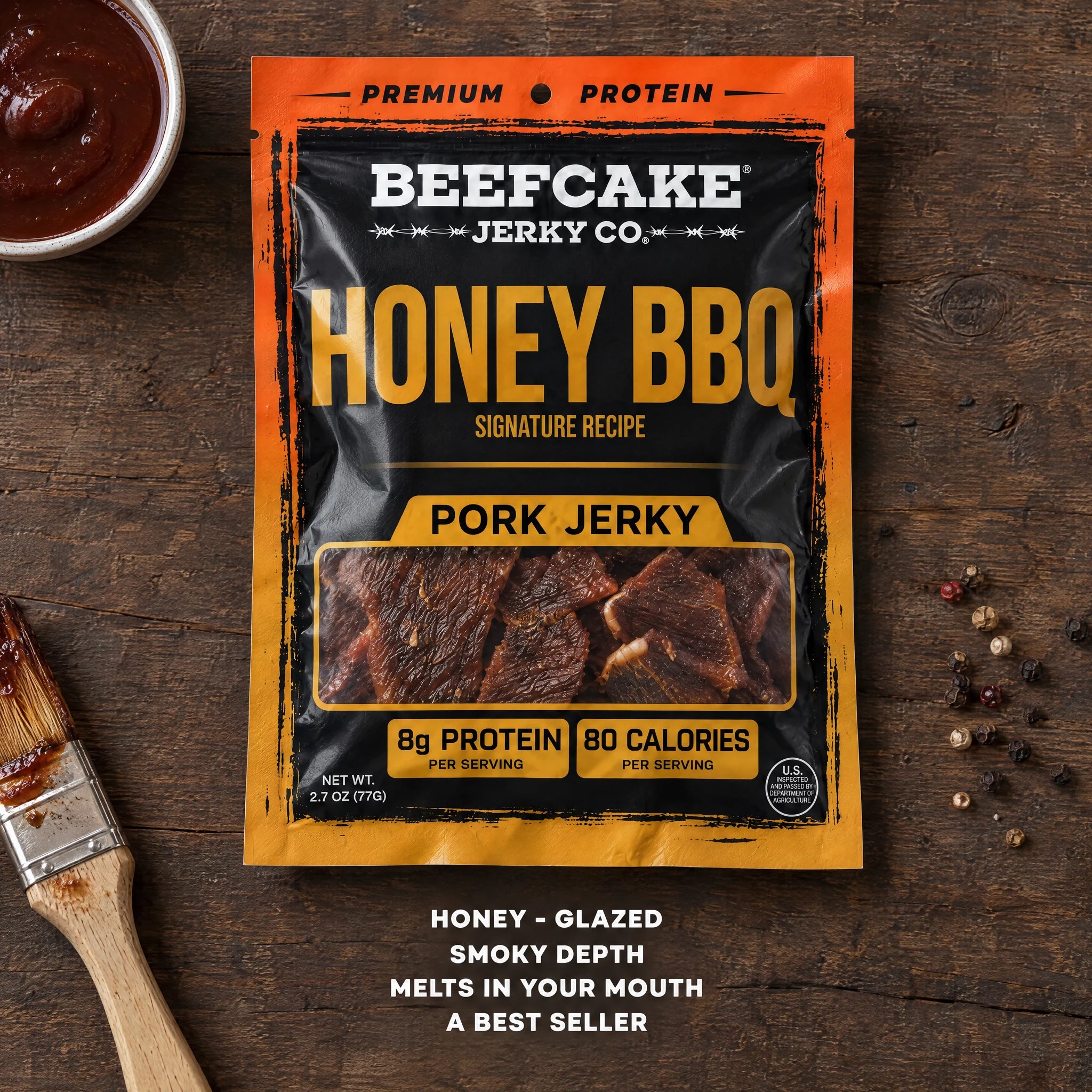 BeefCake Honey BBQ pork jerky with barbecue sauce and a basting brush on a wooden table.