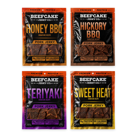 Four BeefCake pork jerky bags laid flat in a clean grid: Honey BBQ, Hickory BBQ, Teriyaki and Sweet Heat, with soft shadows on a transparent background.