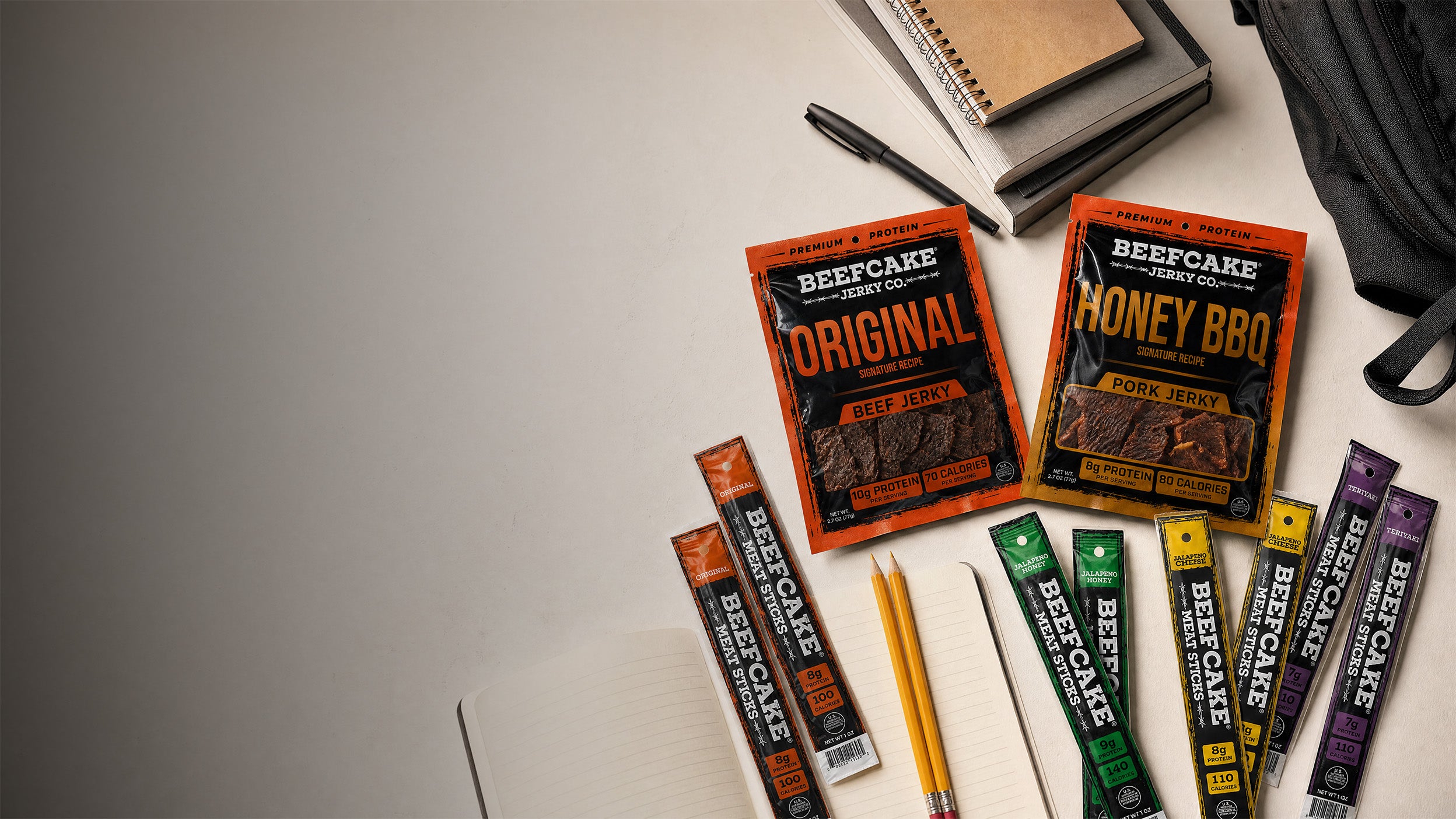BeefCake jerky and Meat Sticks arranged with notebooks, pencils, and a backpack for Back-to-School.